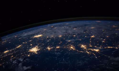 A vast cloud computing data centre at night with thousands of illuminated server racks stretching into the distance under a vaulted ceiling — representing the massive AWS infrastructure commitment at the heart of the Amazon-Anthropic $33 billion deal, which will deploy up to 5 gigawatts of custom Trainium AI compute for Claude model training and inference.